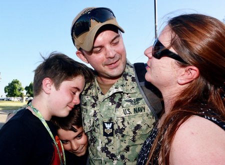 Joshua Burton hugs his family after 8-month deployment.